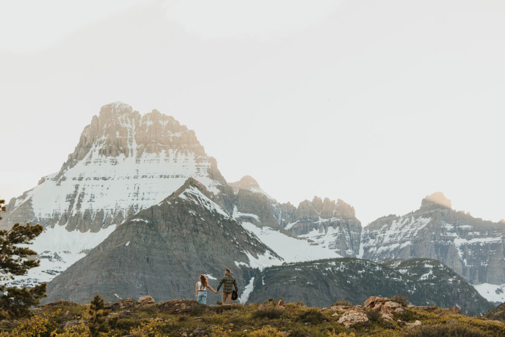 Engagement session on a cliff overlooking snowcapped mountains
