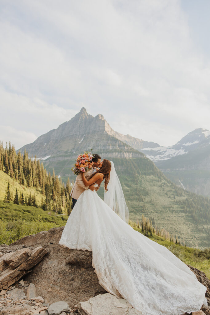 Bride and groom kissing on rock