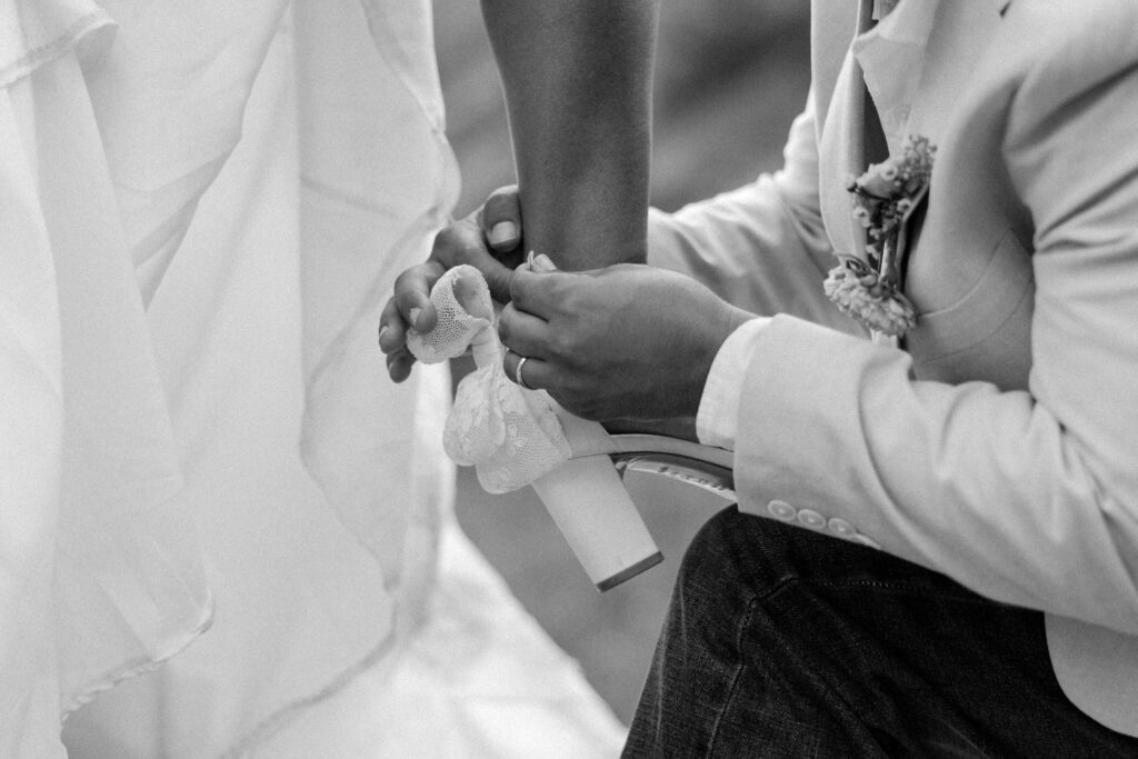 black and white of groom helping bride with her shoe