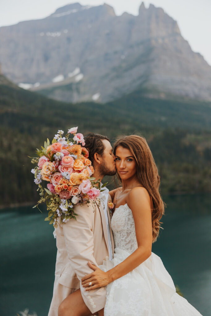 Groom kissing brides cheek at sun point