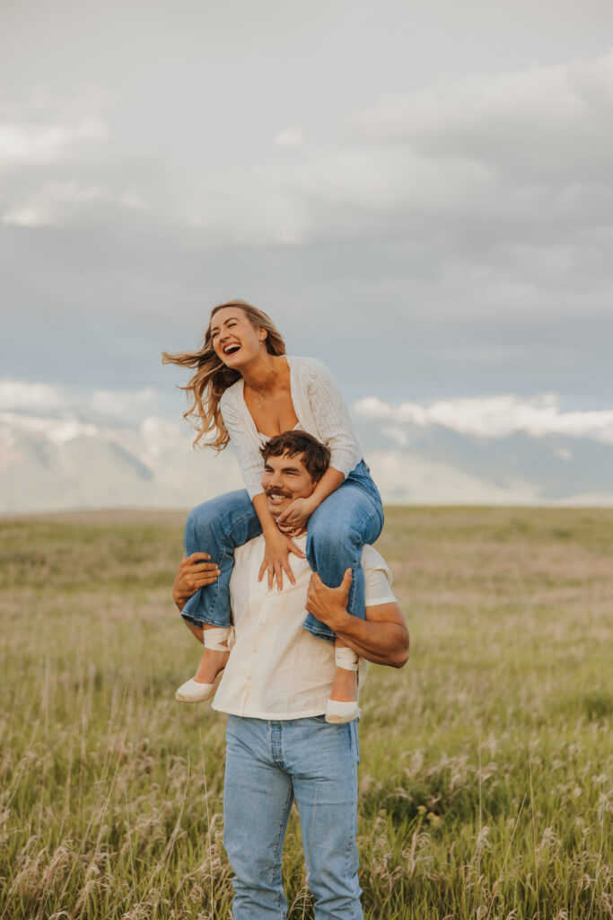A woman on a mans shoulders laughing having fun