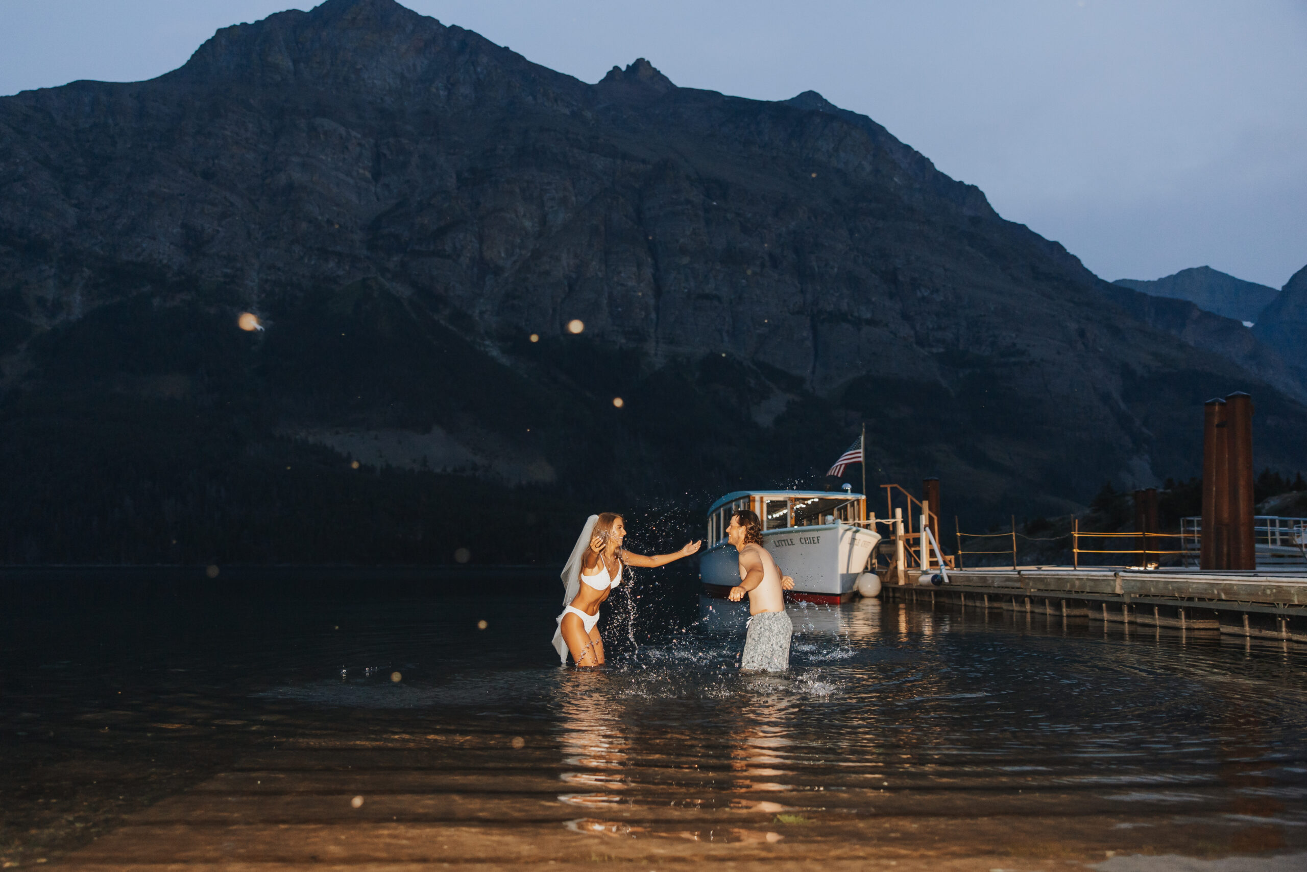 Newly weds jump in the lake after their elopement celebration in Glacier National Park